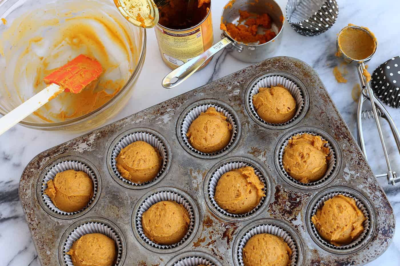 Super moist and perfectly spiced, this pumpkin muffins recipe features a crispy, buttery oat streusel dotted with melty chocolate chips. Overhead view of pumpkin muffin batter inside the lined wells of a muffin pan.