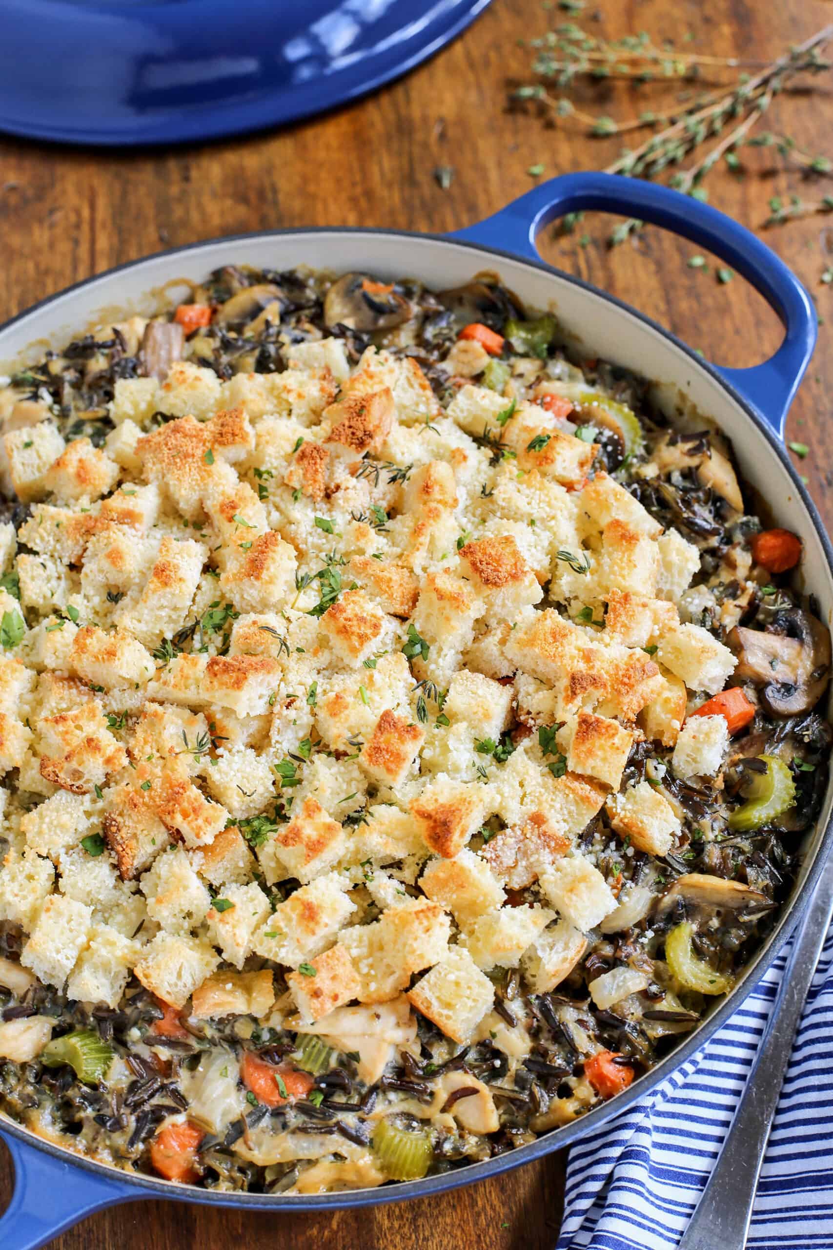 This creamy chicken wild rice casserole is easy comfort food loaded with veggies, melty gruyere cheese, and a buttery crouton topping! Chicken wild rice casserole in a blue casserole dish