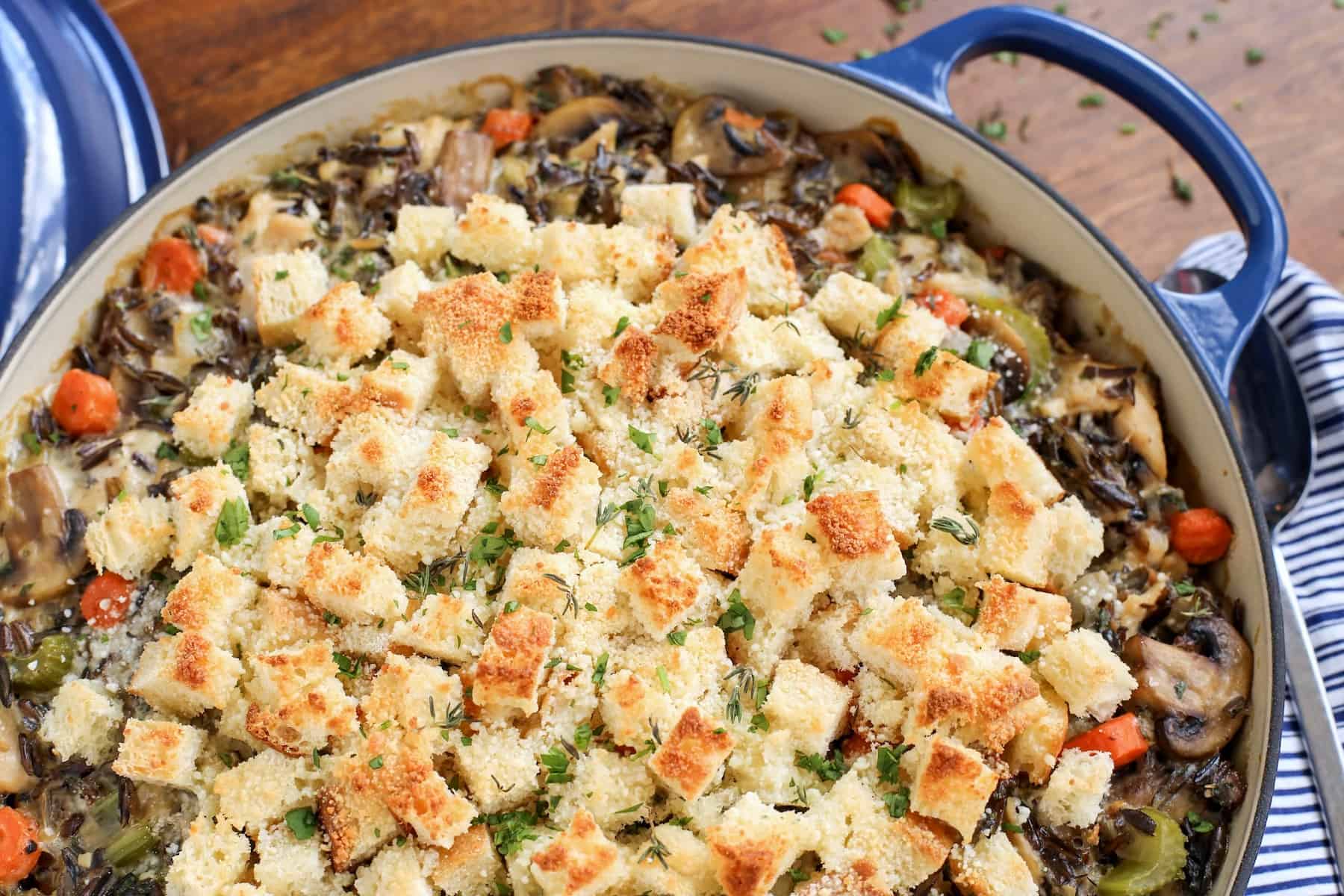 This creamy chicken wild rice casserole is easy comfort food loaded with veggies, melty gruyere cheese, and a buttery crouton topping! Close up of chicken wild rice casserole