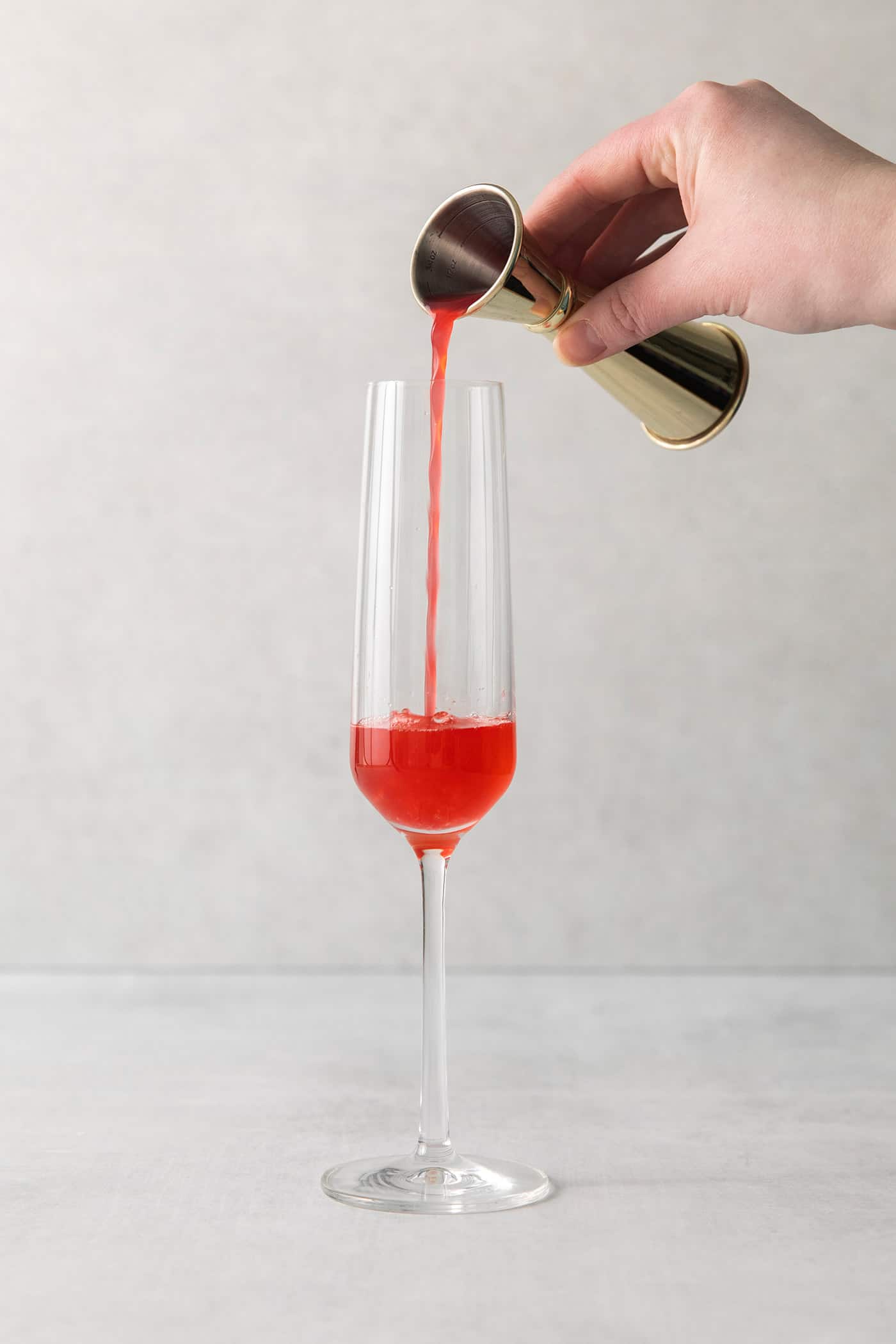 This Blood Orange Mimosa with St. Germain is bursting with fresh, bright flavor. It's super simple to make and the gorgeous color! Blood orange juice being poured into a champagne flute