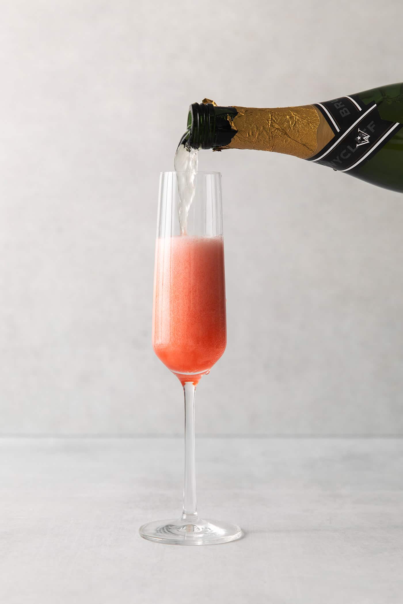 This Blood Orange Mimosa with St. Germain is bursting with fresh, bright flavor. It's super simple to make and the gorgeous color! Champagne being poured into a champagne flute