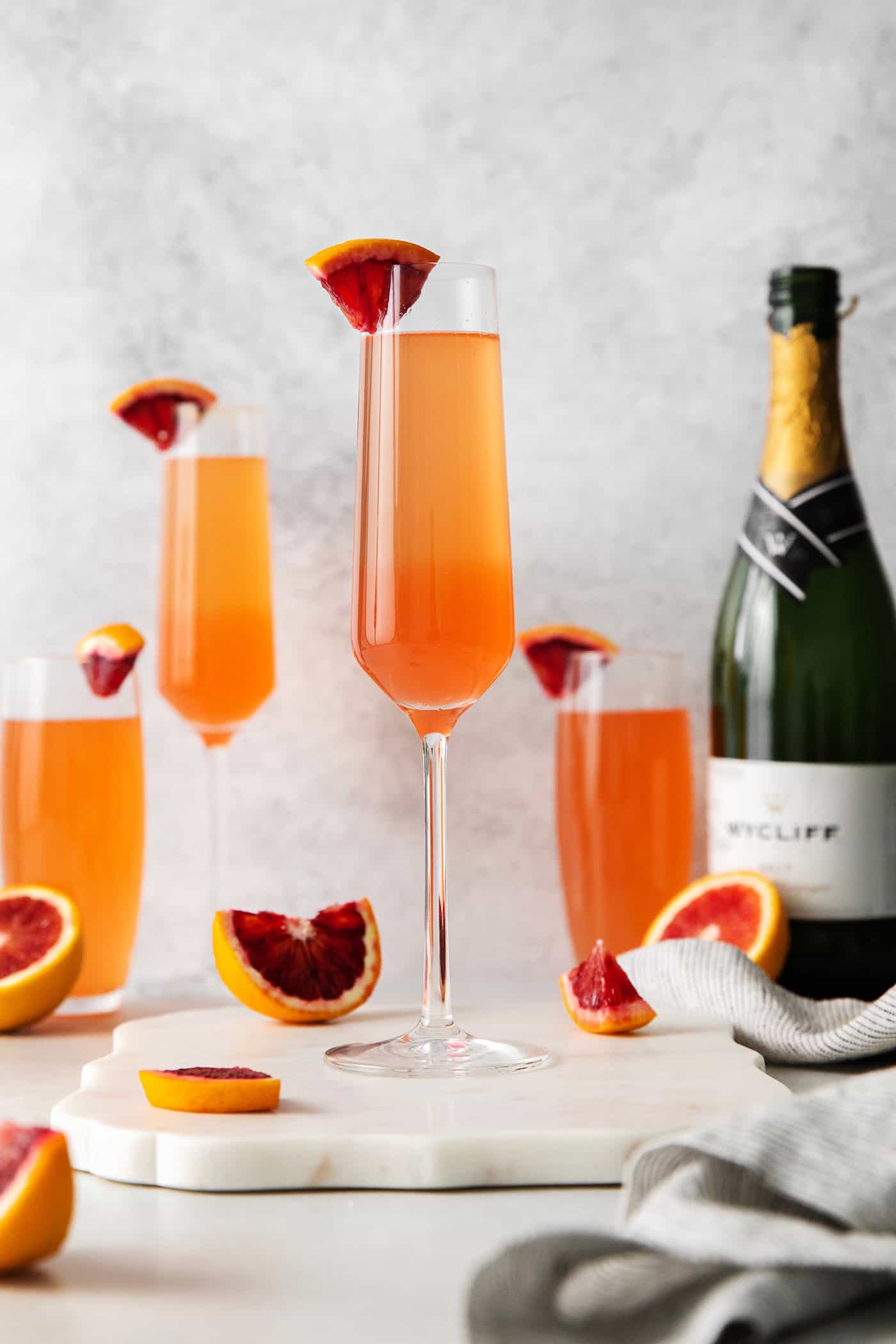 This Blood Orange Mimosa with St. Germain is bursting with fresh, bright flavor. It's super simple to make and the gorgeous color! Blood Orange mimosas next to a champagne bottle