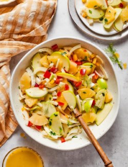 Bowl of fennel apple salad with serving portioned onto plate.
