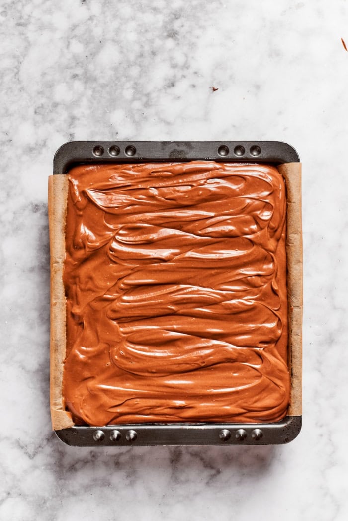 These Nutella cheesecake bars top a fudgy brownie base with creamy Nutella cheesecake for a rich, decadent dessert that’s surprisingly easy! Nutella cheesecake bars in pan before baking.