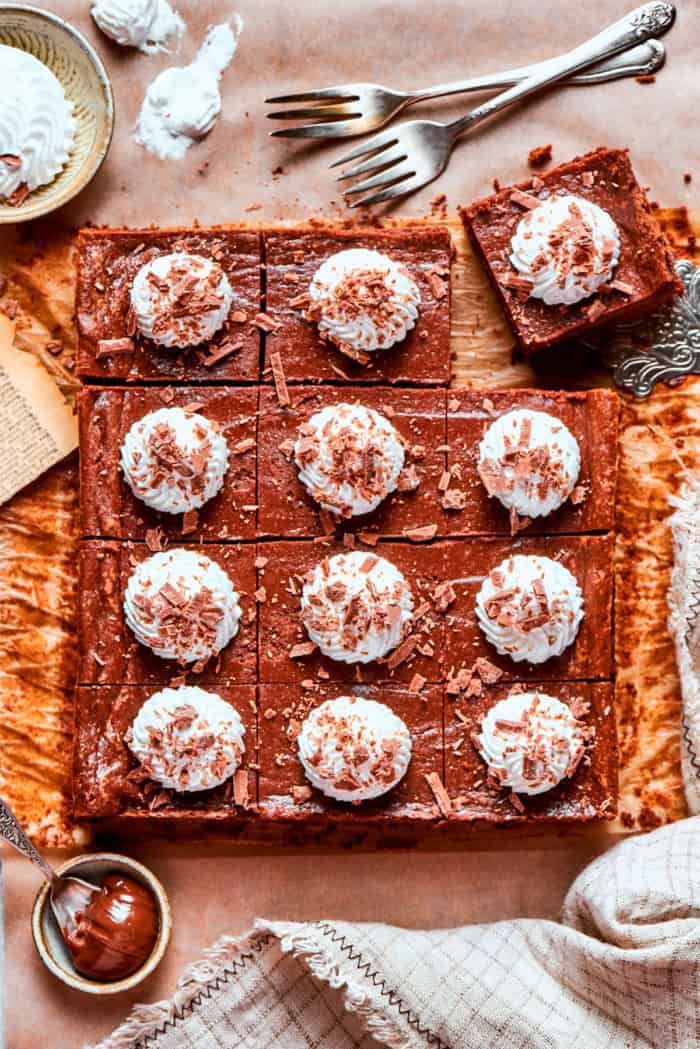 These Nutella cheesecake bars top a fudgy brownie base with creamy Nutella cheesecake for a rich, decadent dessert that’s surprisingly easy! Sliced Nutella cheesecake bars on countertop.