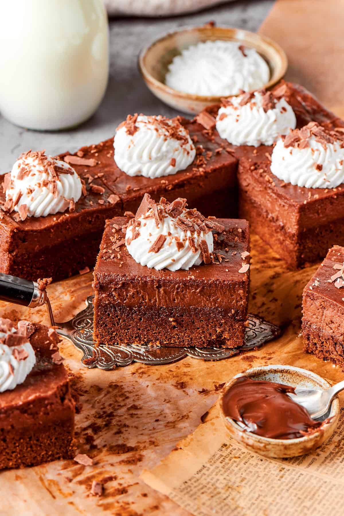 These Nutella cheesecake bars top a fudgy brownie base with creamy Nutella cheesecake for a rich, decadent dessert that’s surprisingly easy! Nutella cheesecake bar held on cake server.