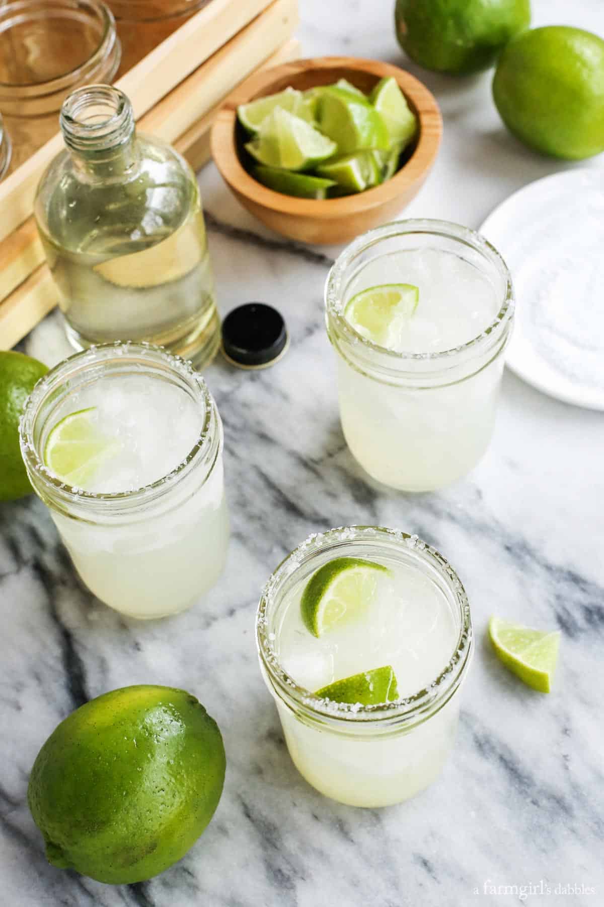 This Classic Margarita Recipe is the only one you'll ever need, whether you want a single drink or a pitcher to share. three mason jars of Margarita with simple syrup and limes