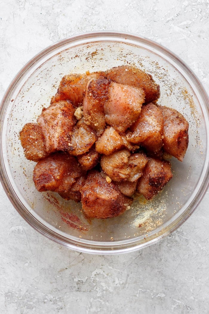 Grilled Hawaiian chicken kabobs have the perfect balance of heat and sweet, with pineapple, red pepper, red onions and savory bacon. Yum! Overhead view of chicken marinating in bowl