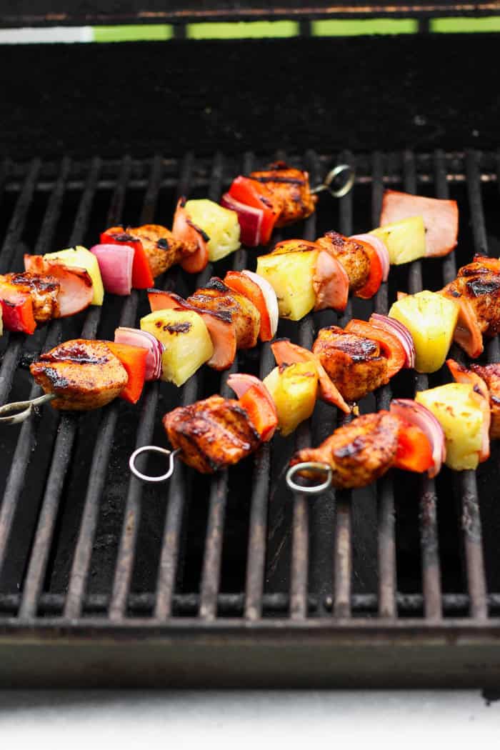 Grilled Hawaiian chicken kabobs have the perfect balance of heat and sweet, with pineapple, red pepper, red onions and savory bacon. Yum! Hawaiian chicken kabobs cooking on grill