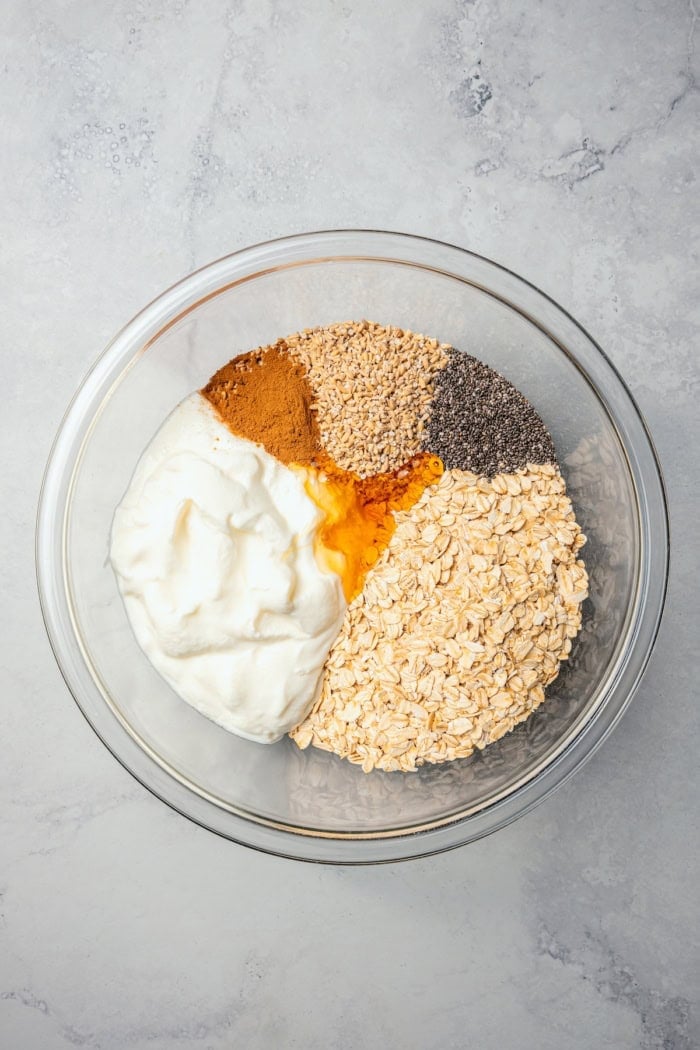 This Apple Cinnamon Overnight Oats recipe is an easy make-ahead breakfast, with the creamiest oats and lots of cozy, tender apples! Overhead view of ingredients for apple cinnamon overnight oats in bowl before stirring