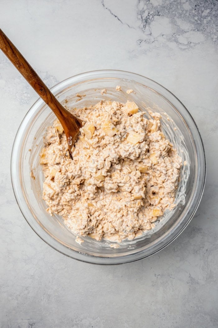 This Apple Cinnamon Overnight Oats recipe is an easy make-ahead breakfast, with the creamiest oats and lots of cozy, tender apples! Overhead view of overnight oats mixture in bowl with wooden spoon