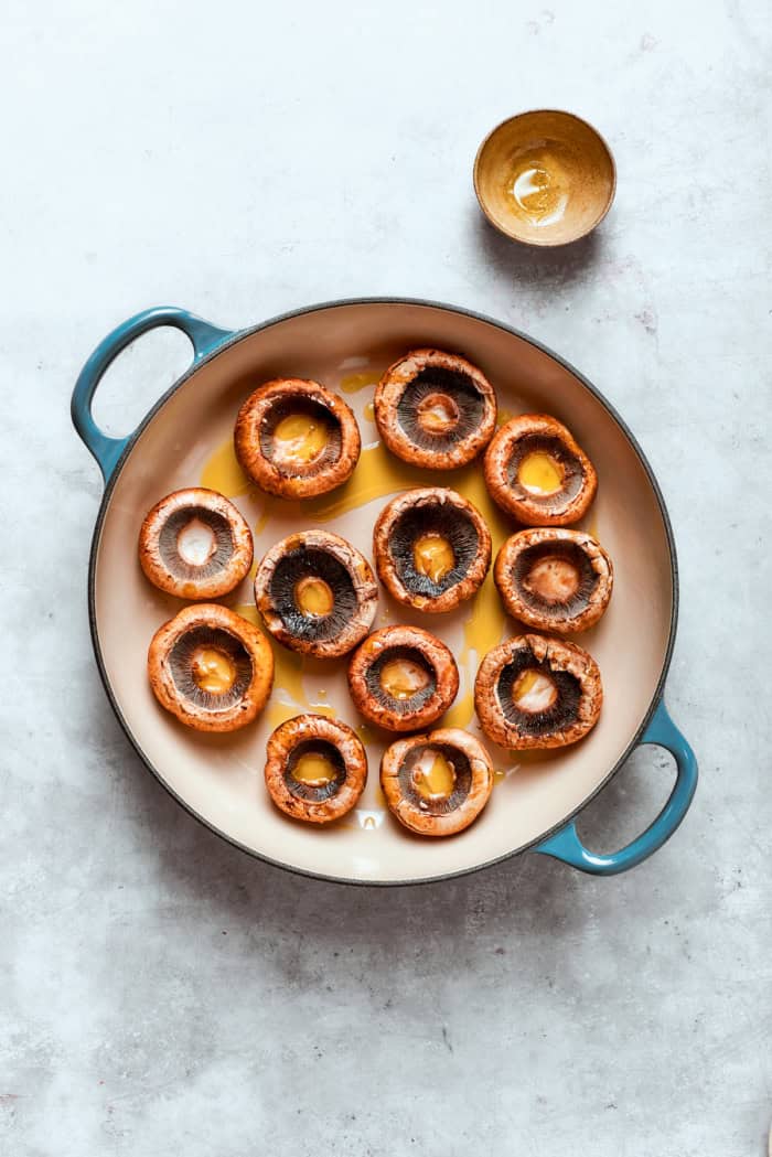 These easy Cheesy Stuffed Mushrooms are an irresistible appetizer or side dish, with lots of melty cheese and garlicky breadcrumbs. Yum! Overhead view of mushroom caps drizzled with olive oil in skillet
