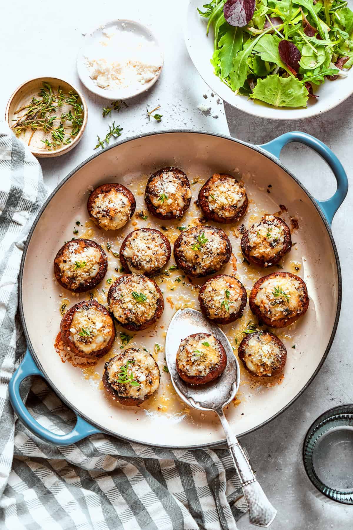 These easy Cheesy Stuffed Mushrooms are an irresistible appetizer or side dish, with lots of melty cheese and garlicky breadcrumbs. Yum! Skillet of cheesy stuffed mushrooms with serving spoon