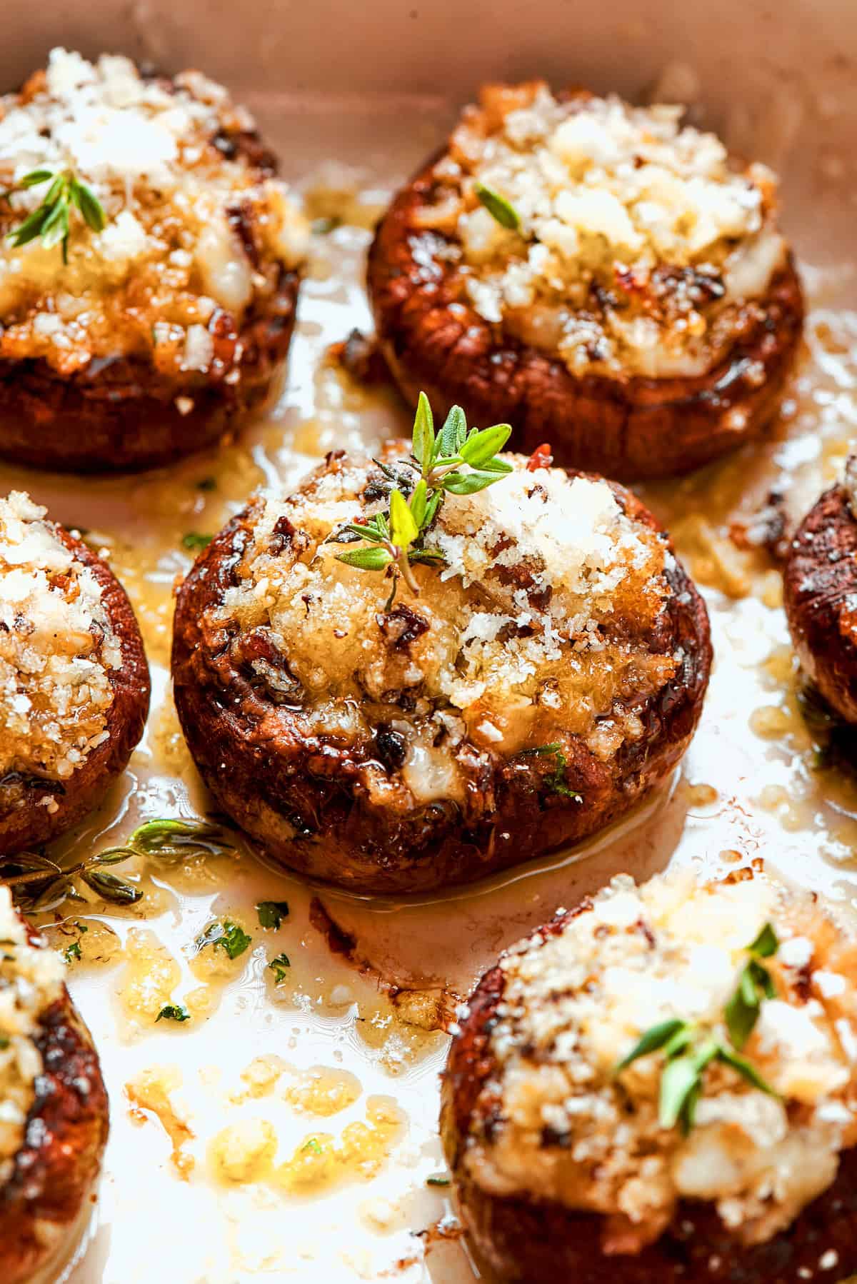 These easy Cheesy Stuffed Mushrooms are an irresistible appetizer or side dish, with lots of melty cheese and garlicky breadcrumbs. Yum! Closeup of cheesy stuffed mushroom with thyme