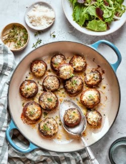 Cheesy stuffed mushrooms in skillet with serving spoon