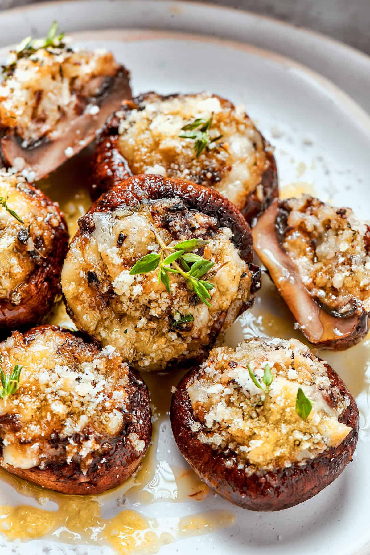 These easy Cheesy Stuffed Mushrooms are an irresistible appetizer or side dish, with lots of melty cheese and garlicky breadcrumbs. Yum! Closeup of cheesy stuffed mushrooms on plate