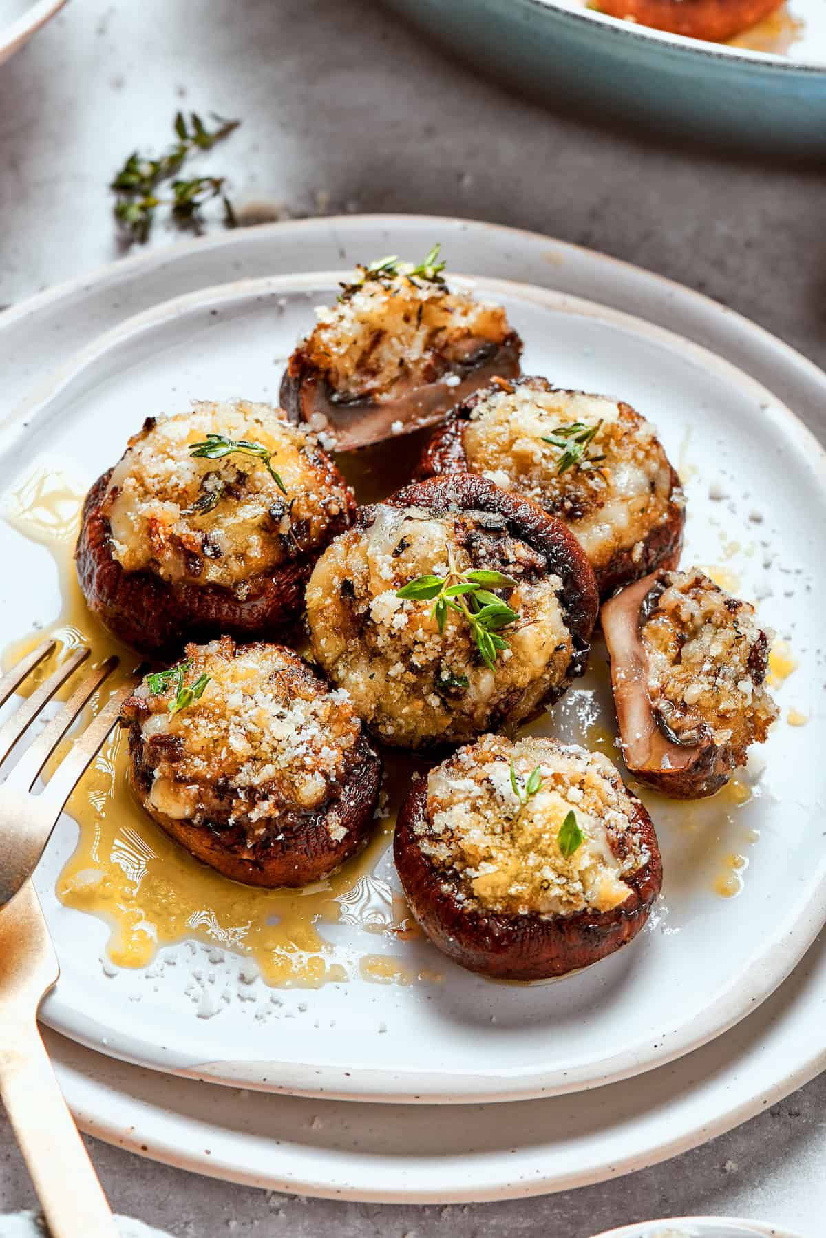 These easy Cheesy Stuffed Mushrooms are an irresistible appetizer or side dish, with lots of melty cheese and garlicky breadcrumbs. Yum! Plate of cheesy stuffed mushrooms