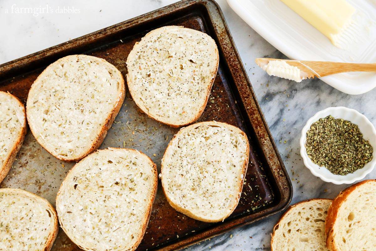 Dip this melty mozzarella-pepperoni pizza grilled cheese recipe into tomato sauce for an easy weeknight dinner that's ready in 12 minutes! Landscape photo of sliced bread on a baking sheet, with butter on the side for spreading and a small bowl of Italian seasoning.