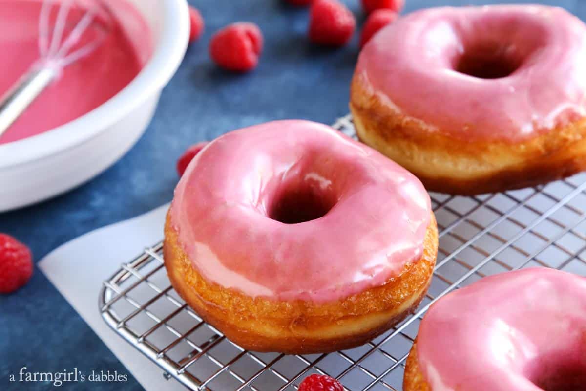 This golden, vanilla-raspberry donuts recipe with sweet lemon glaze is a yummy homemade gift for Valentine's Day. Landscape photo of homemade vanilla donuts with raspberry-lemon glaze.