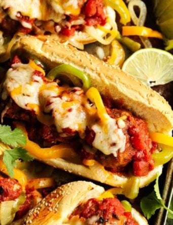Meatball subs with peppers and melted cheese on a baking sheet