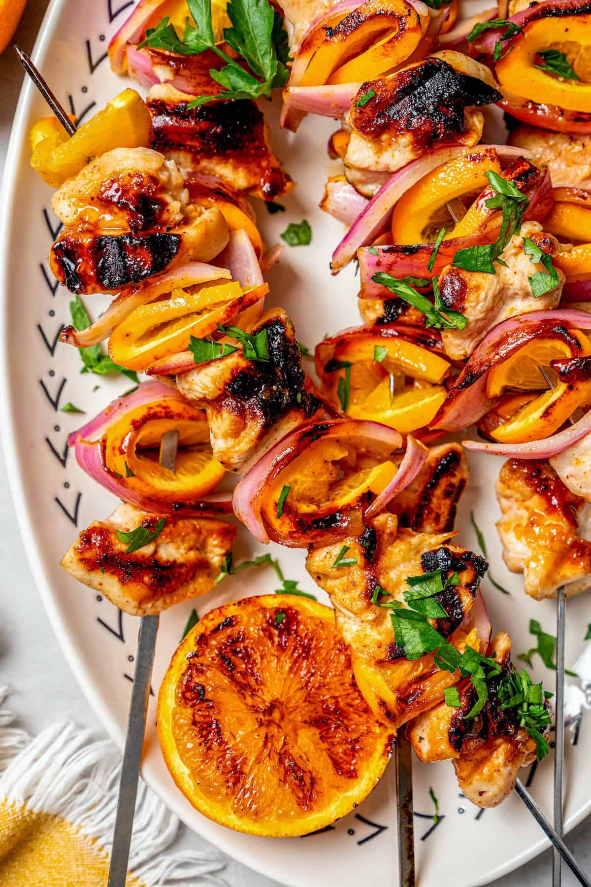Bold, smoky chipotle meets the sweet flavor of orange in these easy Turkey Kabobs. This recipe is a summer staple in my home! Overhead view of grilled chipotle orange turkey kabobs on platter with grilled orange half