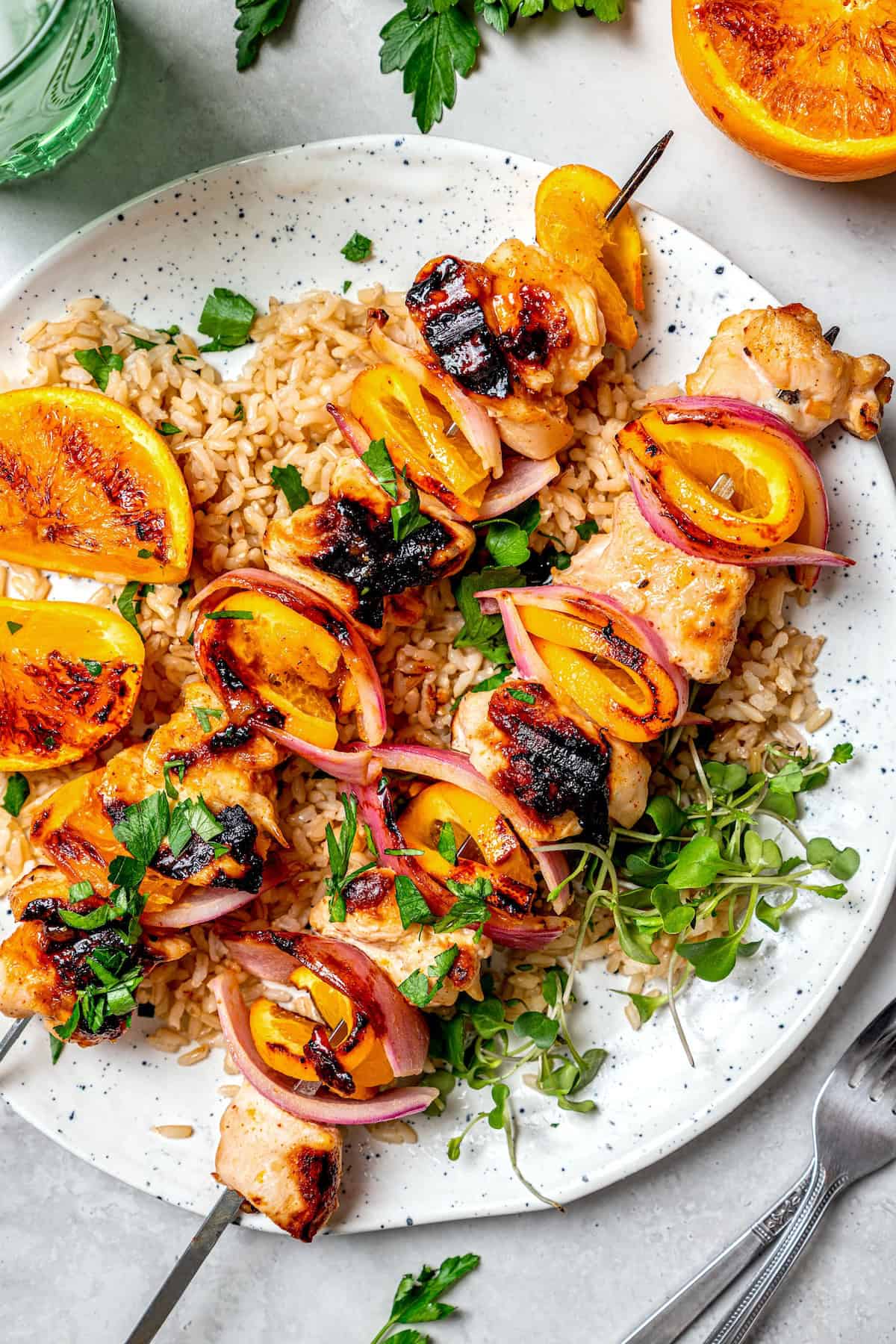 Bold, smoky chipotle meets the sweet flavor of orange in these easy Turkey Kabobs. This recipe is a summer staple in my home! Overhead view of grilled chipotle orange turkey kabobs on plate with rice and microgreens