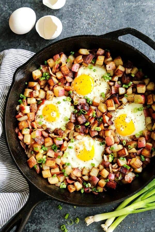 Overhead view of a cast iron skillet with potato hash topped with eggs
