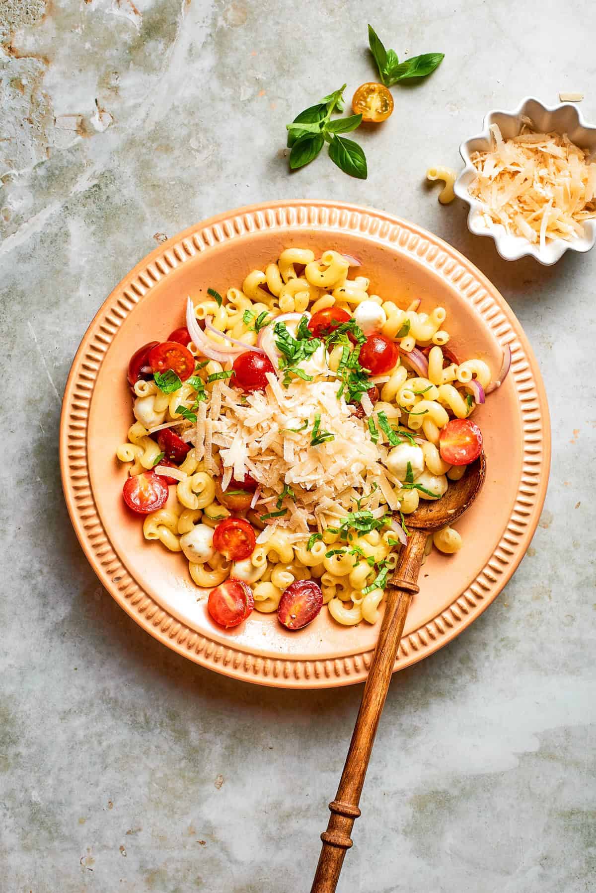 Spoon in bowl with caprese pasta salad.