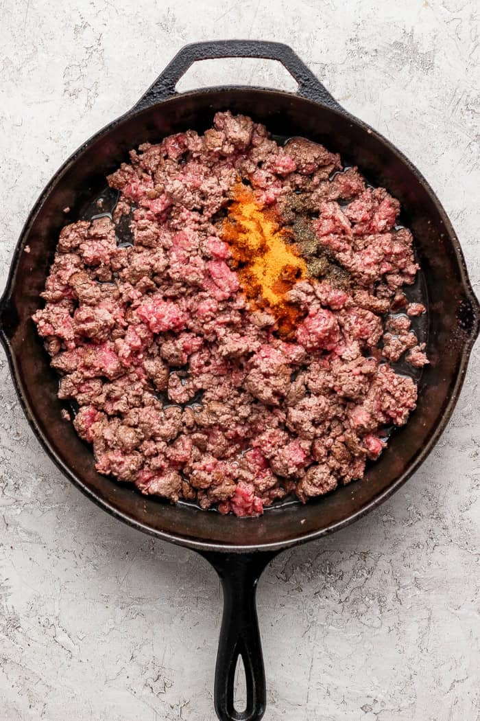 Crispy tater tots, ground beef, smoky bacon and cheese make this bacon cheeseburger tater tot casserole taste like a burger in hot dish form! Seasonings added to skillet of ground beef.