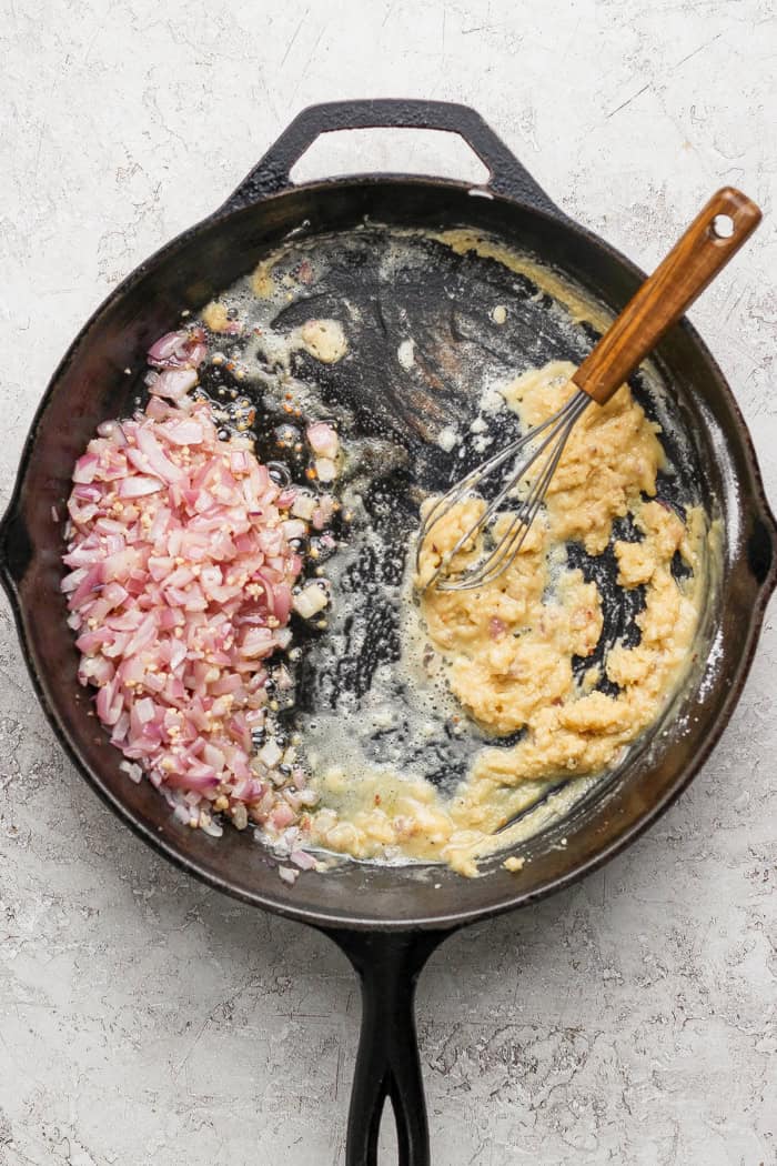 Crispy tater tots, ground beef, smoky bacon and cheese make this bacon cheeseburger tater tot casserole taste like a burger in hot dish form! Whisking roux in skillet with red onions.