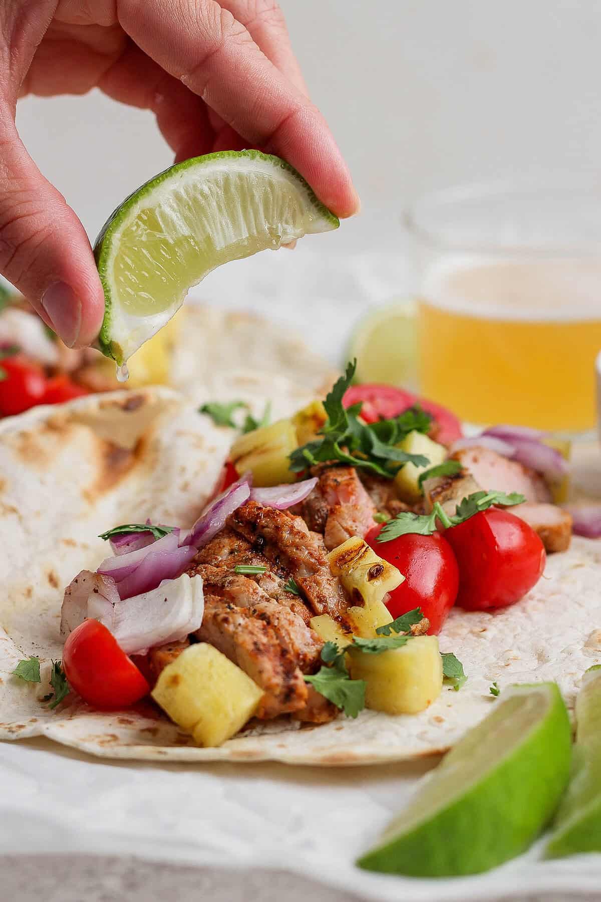 This Grilled Pork and Pineapple Tacos recipe a much easier twist on tacos al pastor. It promises to be your next taco night hit! Squeezing lime juice onto grilled pork and pineapple taco