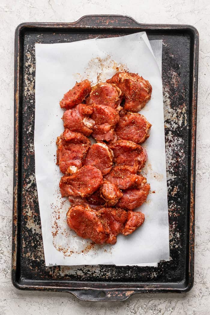 This Grilled Pork and Pineapple Tacos recipe a much easier twist on tacos al pastor. It promises to be your next taco night hit! Overhead view of seasoned pork tenderloin rounds on sheet pan before cooking