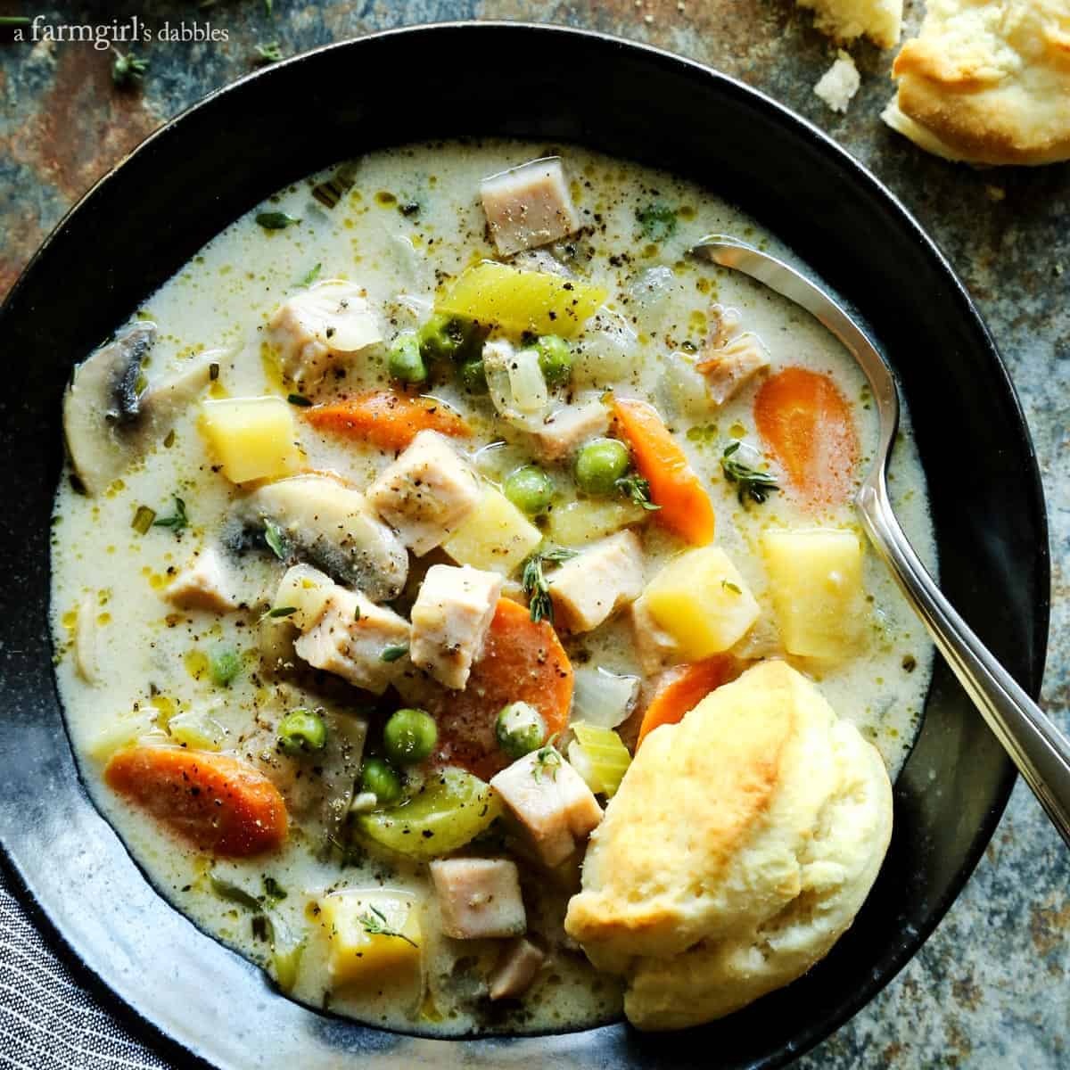 Smoked Turkey Pot Pie Soup is full of rich flavors and creamy comfort, and served with ultra-tender cream biscuits for dipping! Smoked Turkey Pot Pie Soup in a black bowl
