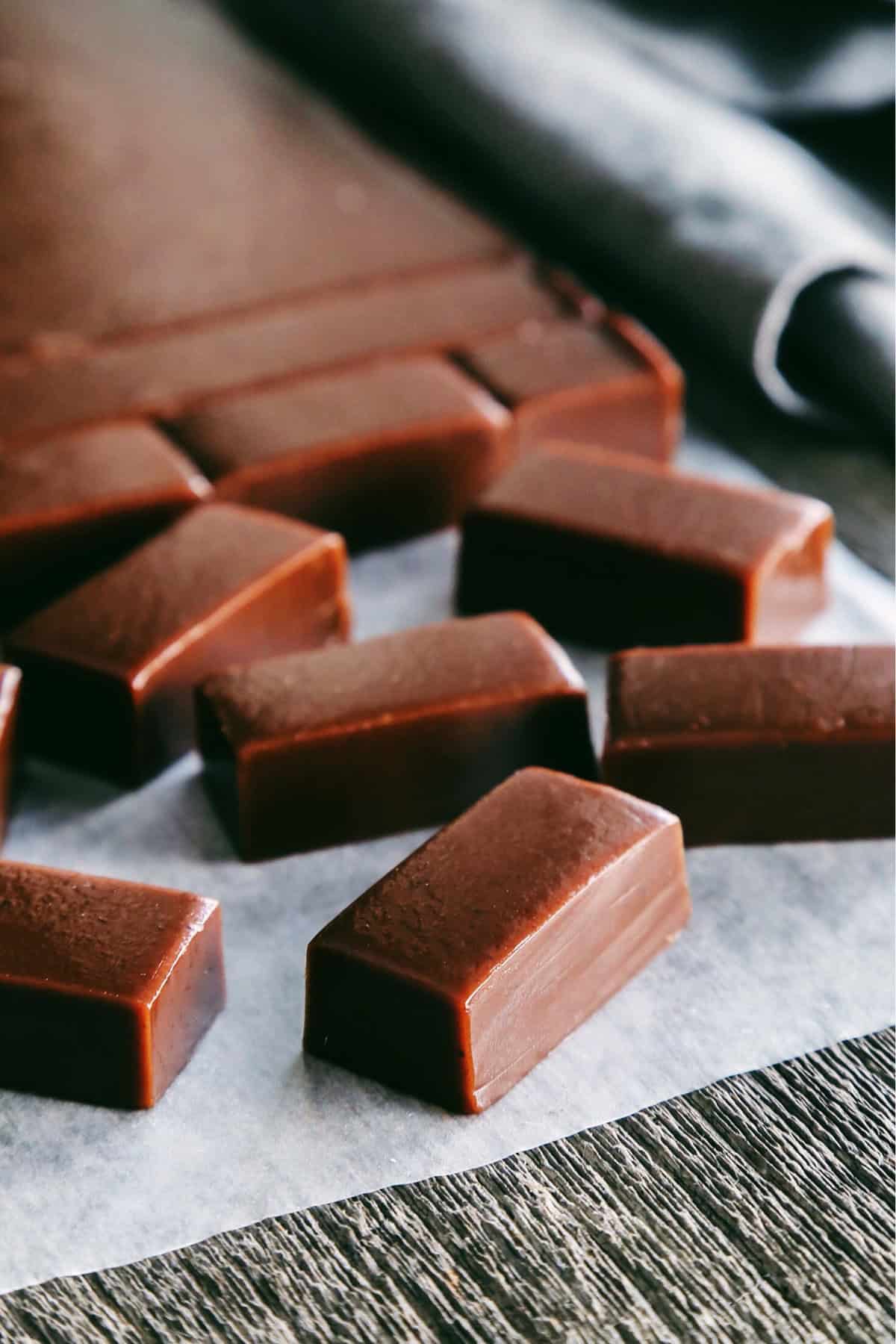 Freshly made, sliced chocolate caramels on a piece of wax paper. 