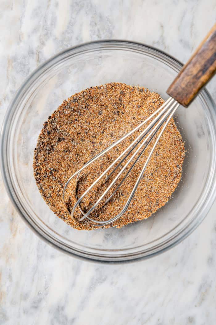 Overhead view of taco seasoning in glass bowl with whisk