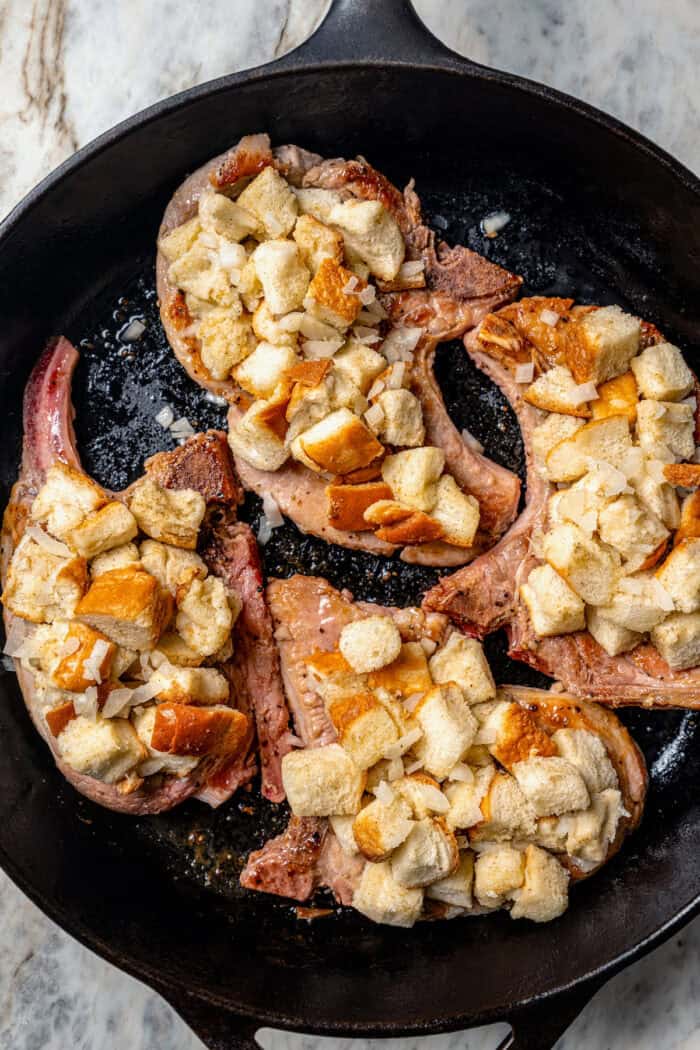 Covering the pork chops with bread stuffing.