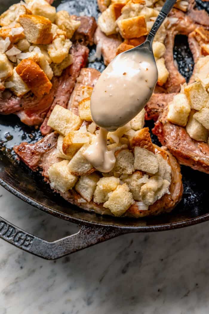 Spooning creamy sauce over the stuffing-topped chops.