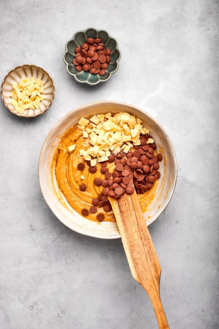 Nutty brown butter, flaky sea salt and fluffy buttercream make this chewy chocolate chip skillet cookie worthy of a celebration. So easy too! Stirring white and dark chocolate chips into dough for skillet cookie.