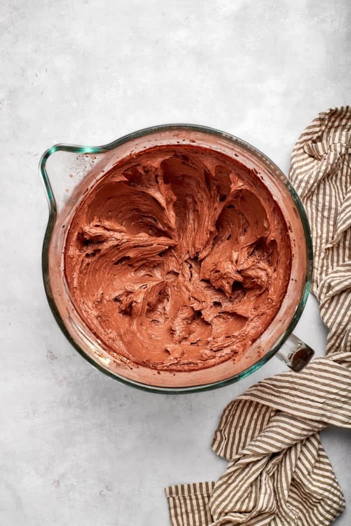 Nutty brown butter, flaky sea salt and fluffy buttercream make this chewy chocolate chip skillet cookie worthy of a celebration. So easy too! Chocolate buttercream in glass mixing bowl.
