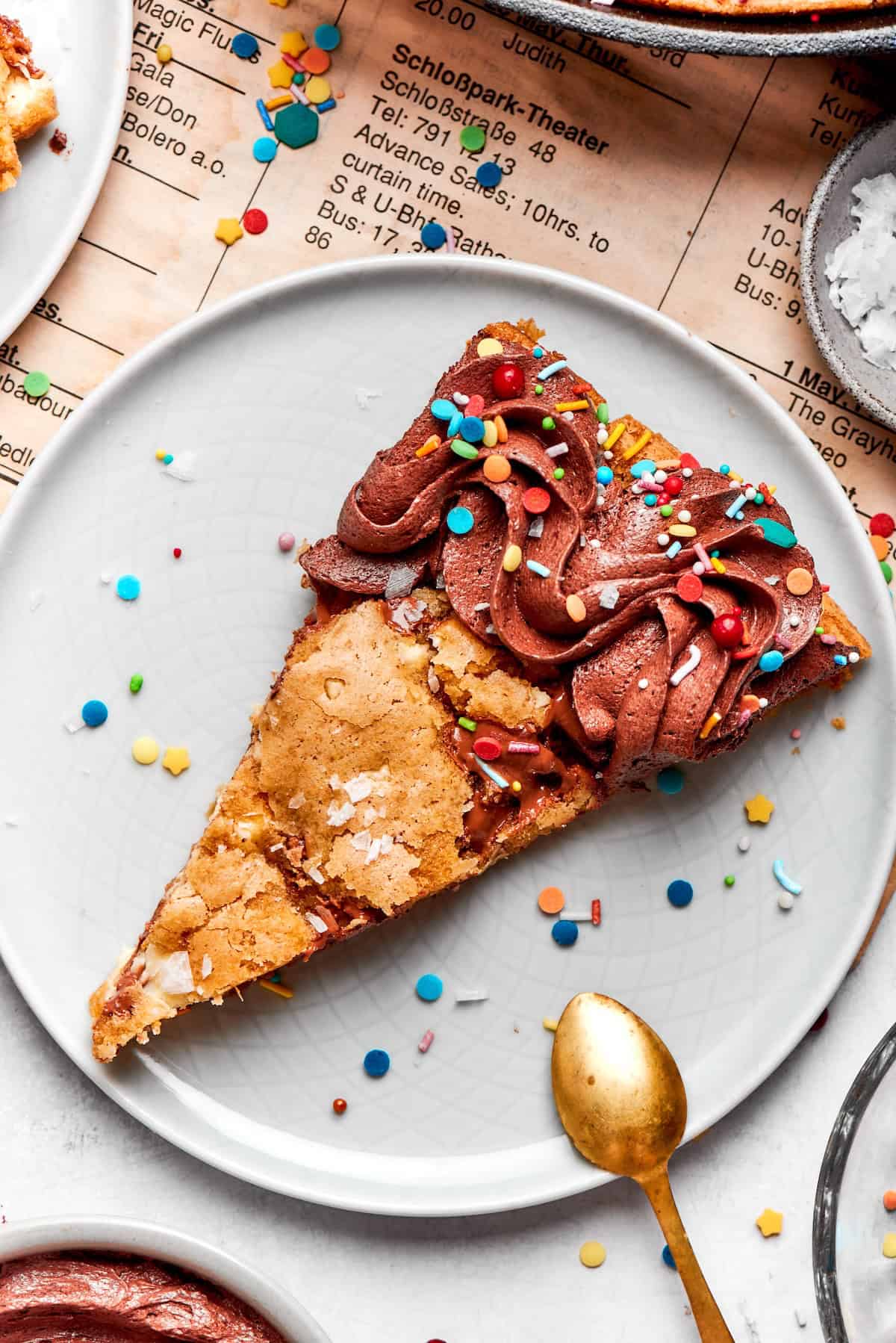 Nutty brown butter, flaky sea salt and fluffy buttercream make this chewy chocolate chip skillet cookie worthy of a celebration. So easy too! Brown butter chocolate chip skillet cookie slice on plate with sprinkles.