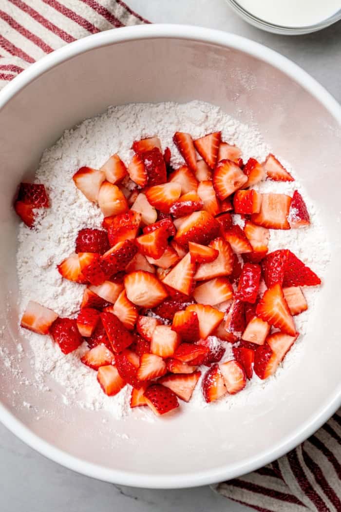These homemade Strawberry Scones are buttery and golden, and studded with fresh berries. A drizzle of vanilla glaze is the perfect finish! Overhead view of strawberries added to dough mixture for scones
