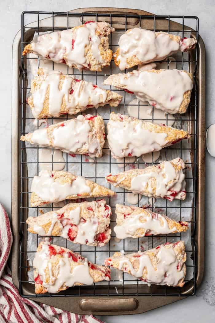 These homemade Strawberry Scones are buttery and golden, and studded with fresh berries. A drizzle of vanilla glaze is the perfect finish! Overhead view of strawberry scones on wire rack