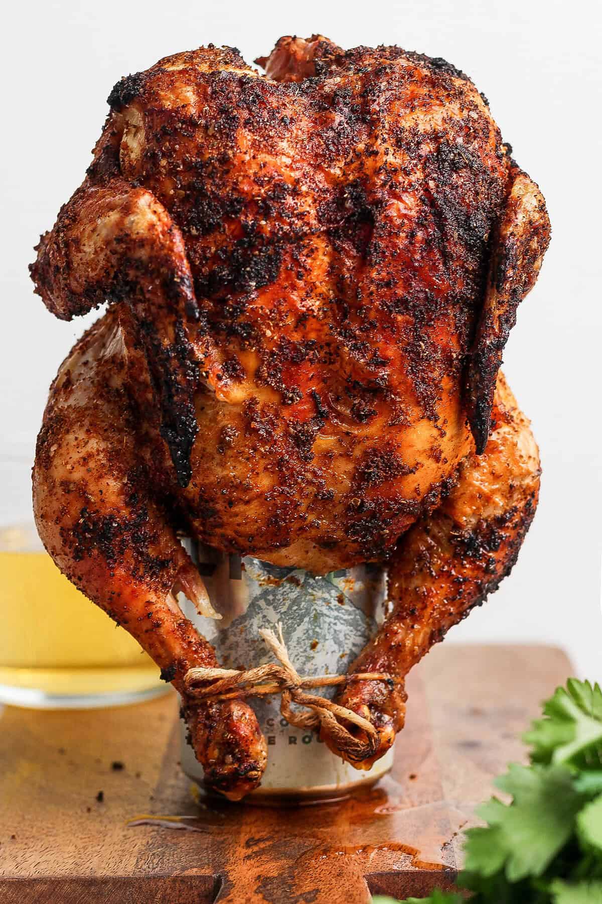 This easy Beer Can Chicken Recipe guarantees moist meat and crispy, flavorful skin. It’s our go-to recipe for a grilled whole chicken! Cooked beer can chicken standing on can