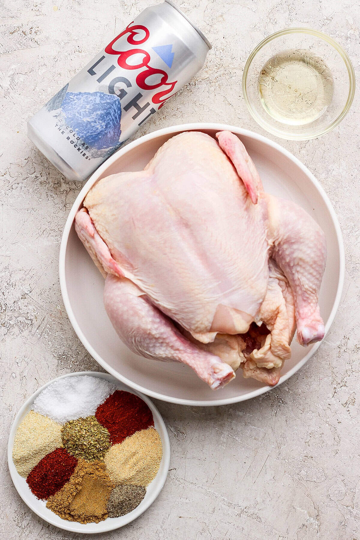 This easy Beer Can Chicken Recipe guarantees moist meat and crispy, flavorful skin. It’s our go-to recipe for a grilled whole chicken! Overhead view of ingredients for beer can chicken
