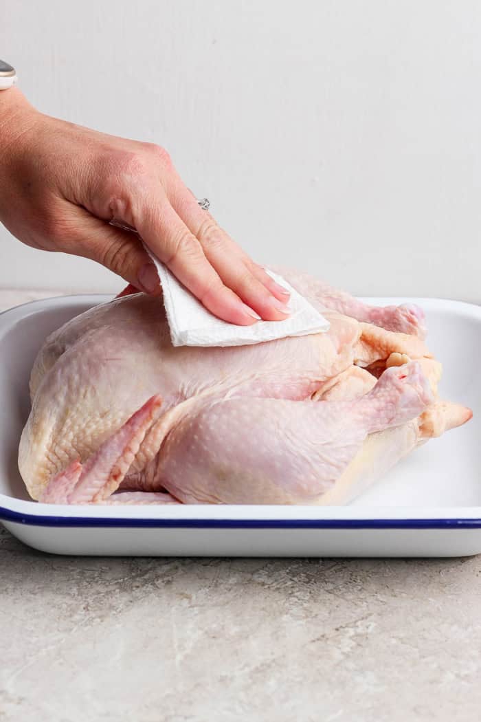 This easy Beer Can Chicken Recipe guarantees moist meat and crispy, flavorful skin. It’s our go-to recipe for a grilled whole chicken! Using paper towels to dry whole chicken in pan