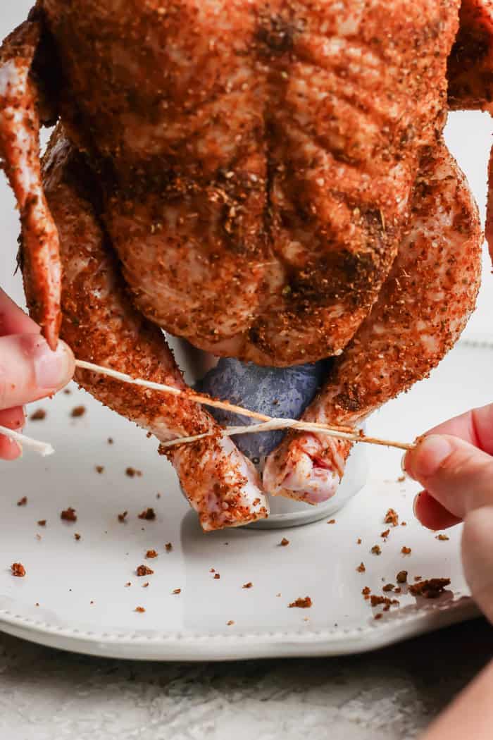 This easy Beer Can Chicken Recipe guarantees moist meat and crispy, flavorful skin. It’s our go-to recipe for a grilled whole chicken! Tying chicken legs to secure it on beer can