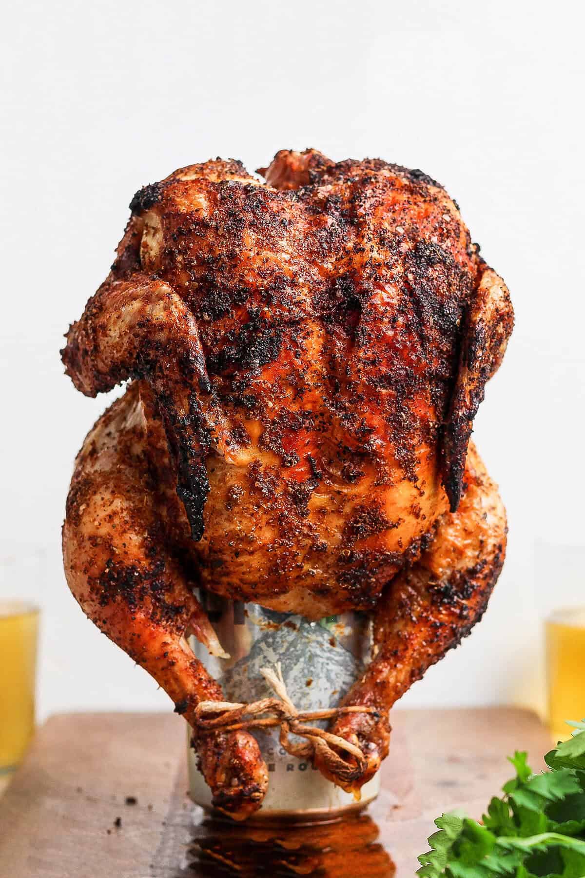 This easy Beer Can Chicken Recipe guarantees moist meat and crispy, flavorful skin. It’s our go-to recipe for a grilled whole chicken! Cooked beer can chicken standing on can