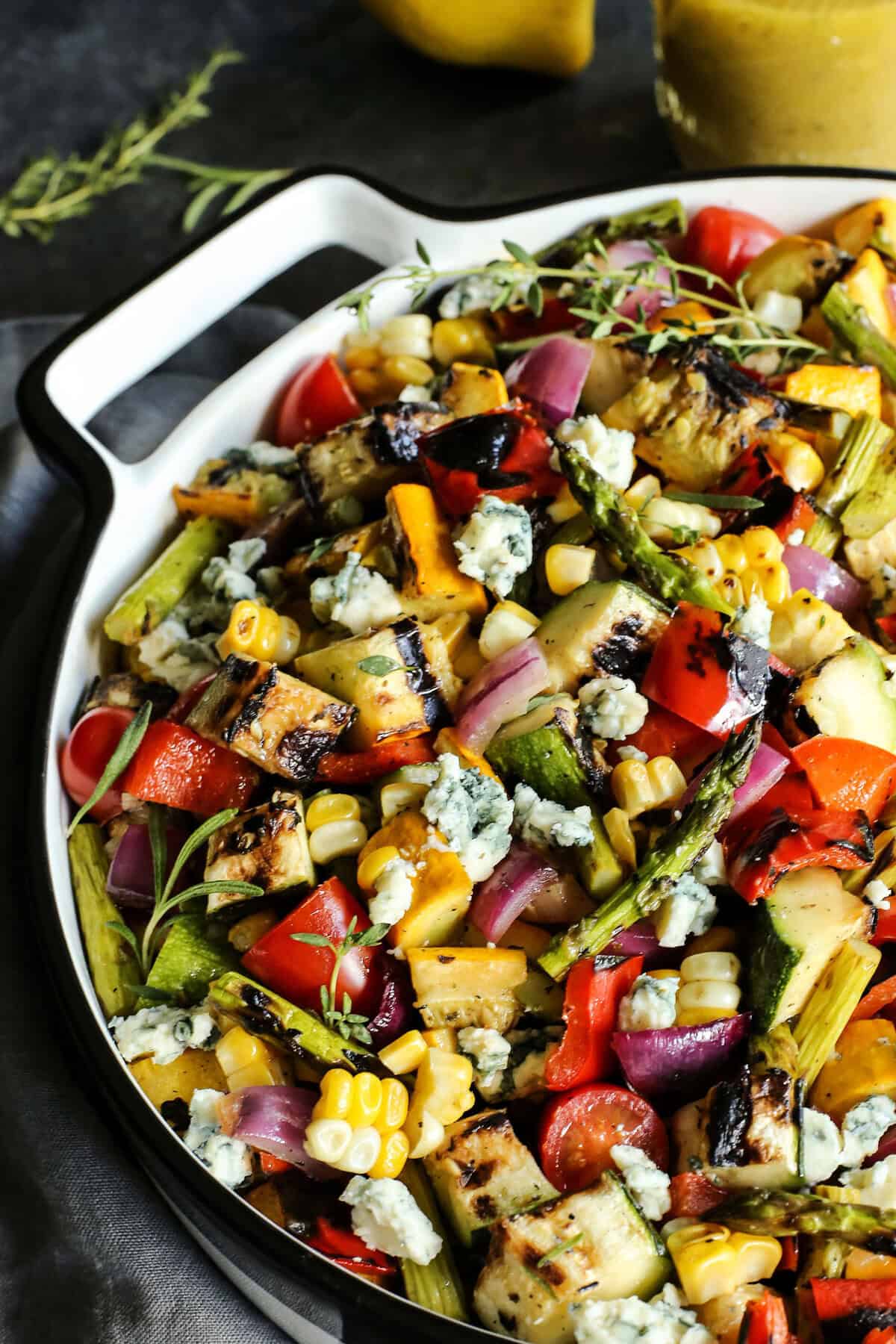 This Grilled Vegetable Salad recipe features smoky veggies, a bright lemon vinaigrette, and blue cheese (or shaved Parmesan). So flavorful! Summer vegetable salad in pan with blue cheese crumbles