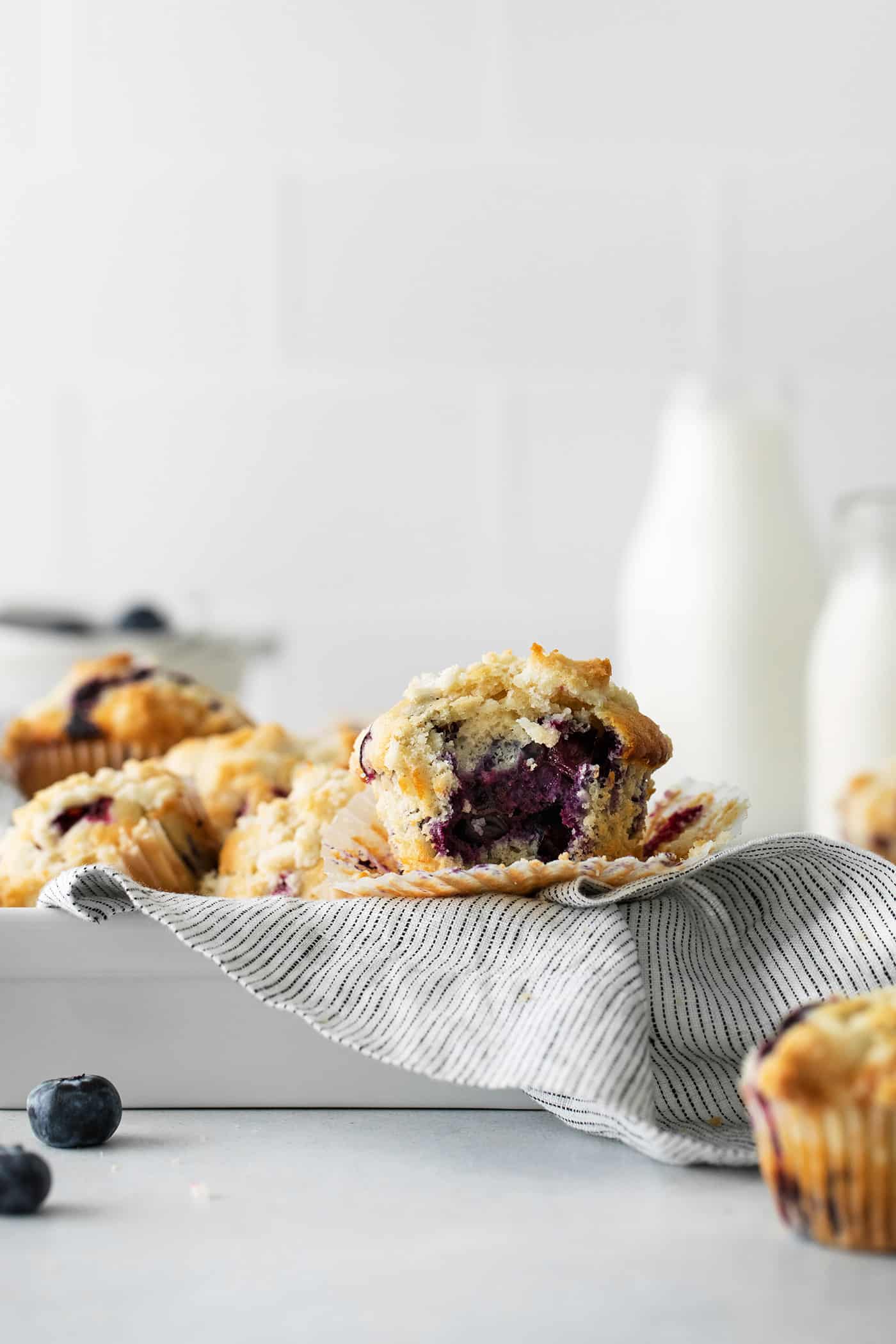 Soft, fluffy, and filled with blueberries, this family recipe makes a batch of the best blueberry muffins topped with a buttery streusel. Blueberry muffins in a metal pan for serving with one cut in half