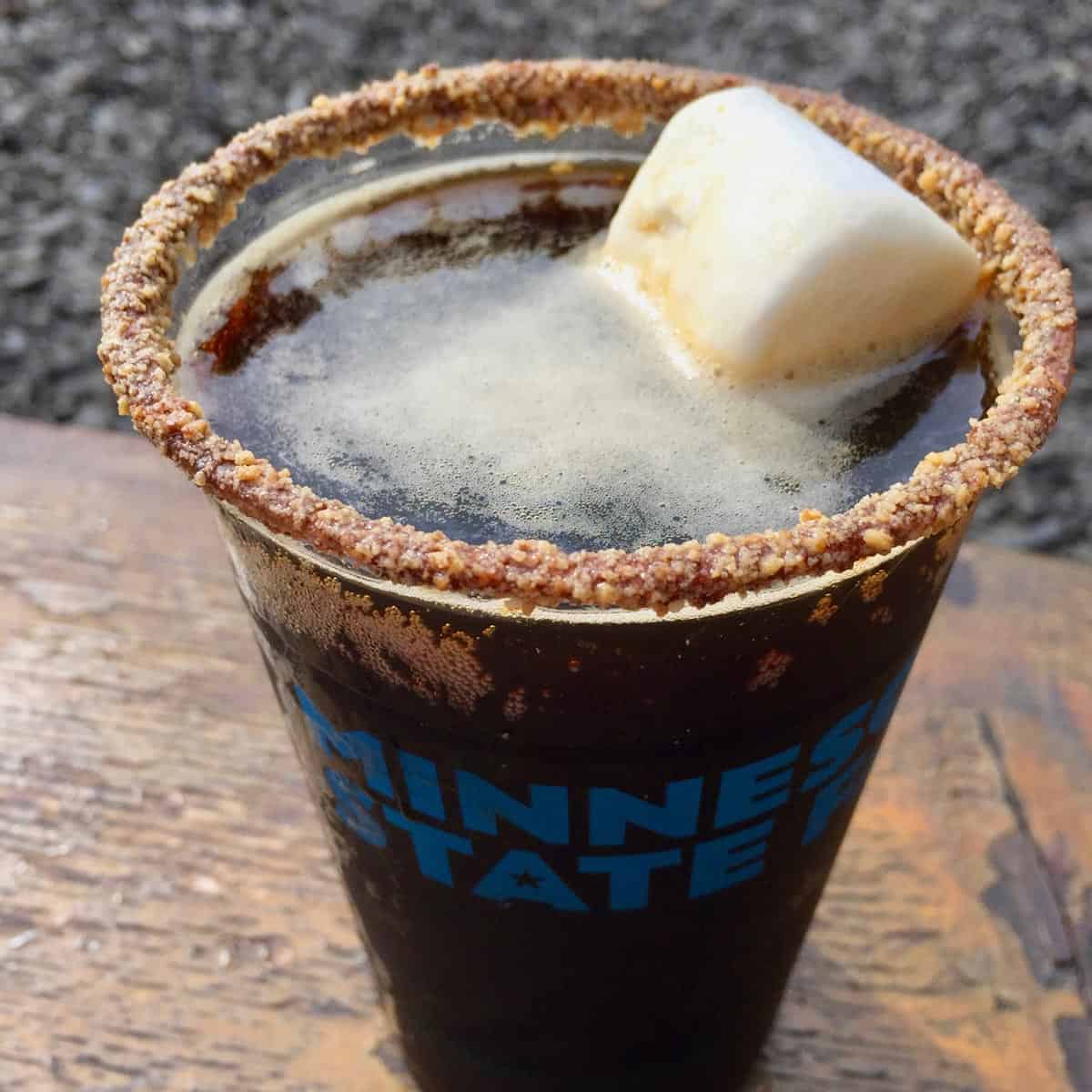 a glass of dark beer with a sugar rim and floating marshmallow
